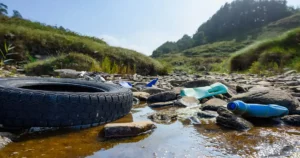 Cours d’eau pollué par des déchets plastiques et un pneu